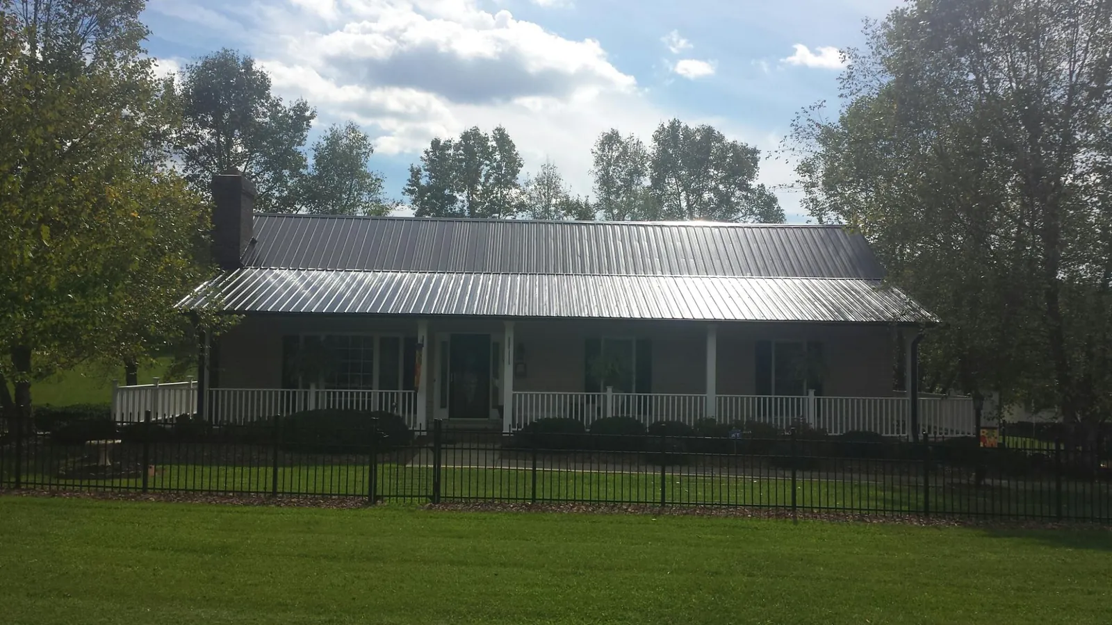 Gray metal roof on a brick ranch with a full width front porch — Gutter Guard Installation work by our crew in Epworth