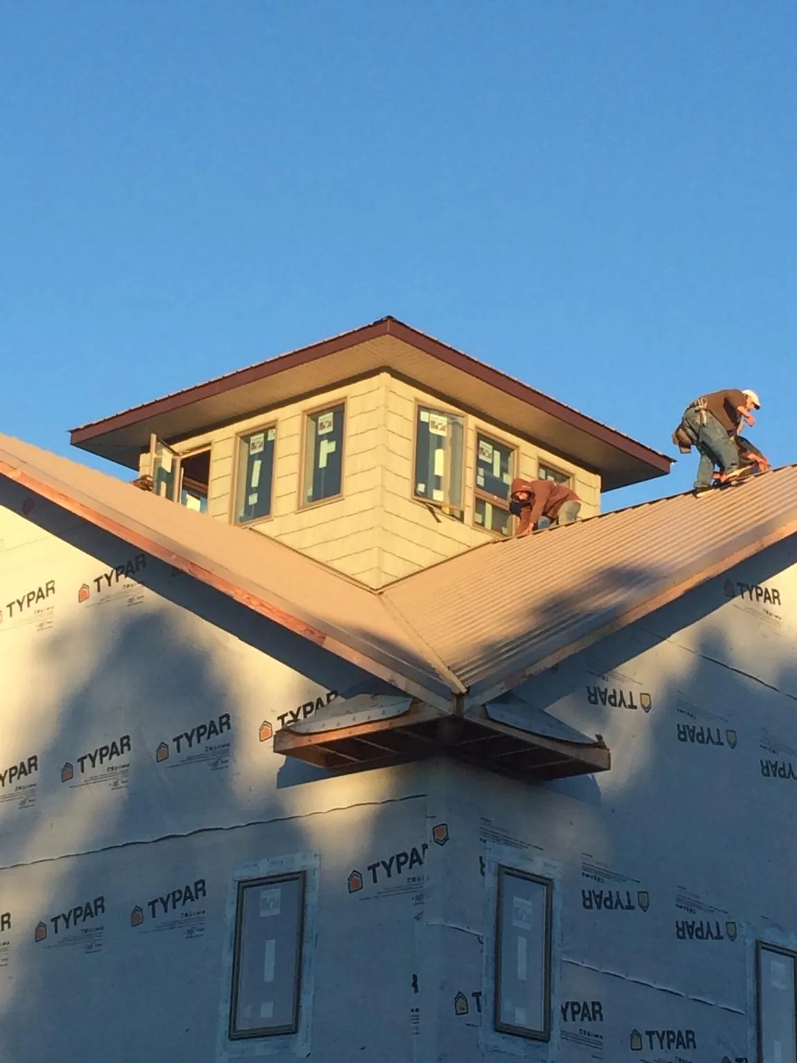 Roofers working around a rooftop cupola on a new metal roof at sunset — Roof Waterproofing in Epworth by Roofing Brothers
